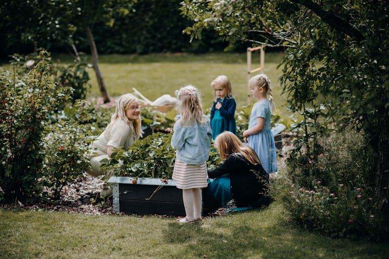 Enfants et adulte jardinent ensemble dans un jardin verdoyant